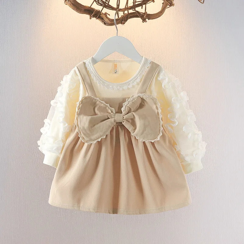 Beige dress with a large bow on a hanger against a neutral background