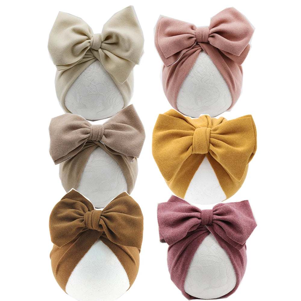 Set of six baby headbands with large bows in various colors on a white background