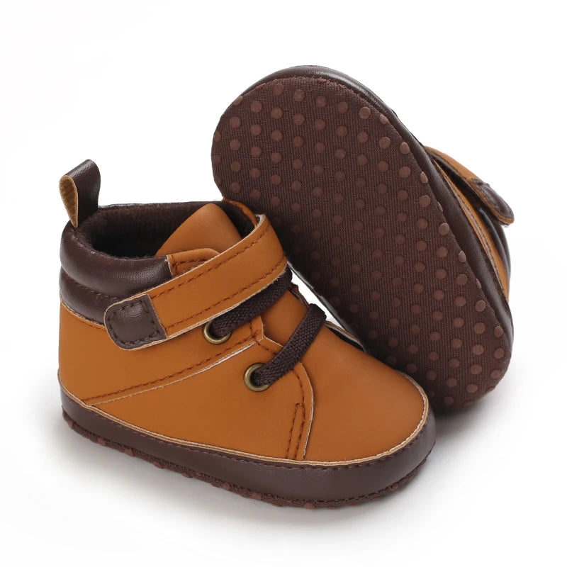 Pair of brown baby shoes with dark brown soles on a white background