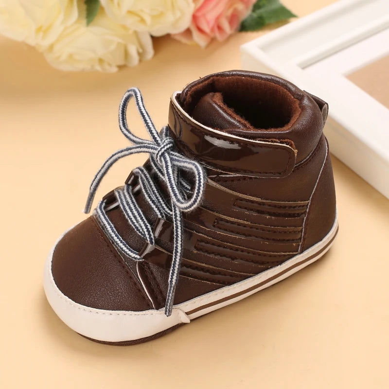 Brown baby bootie with white laces on a beige surface with flowers in the background