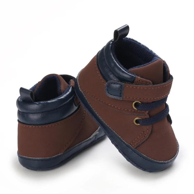Pair of brown and navy baby shoes on a white background