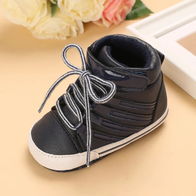 Navy blue baby shoe with white laces on a beige surface with flowers in the background