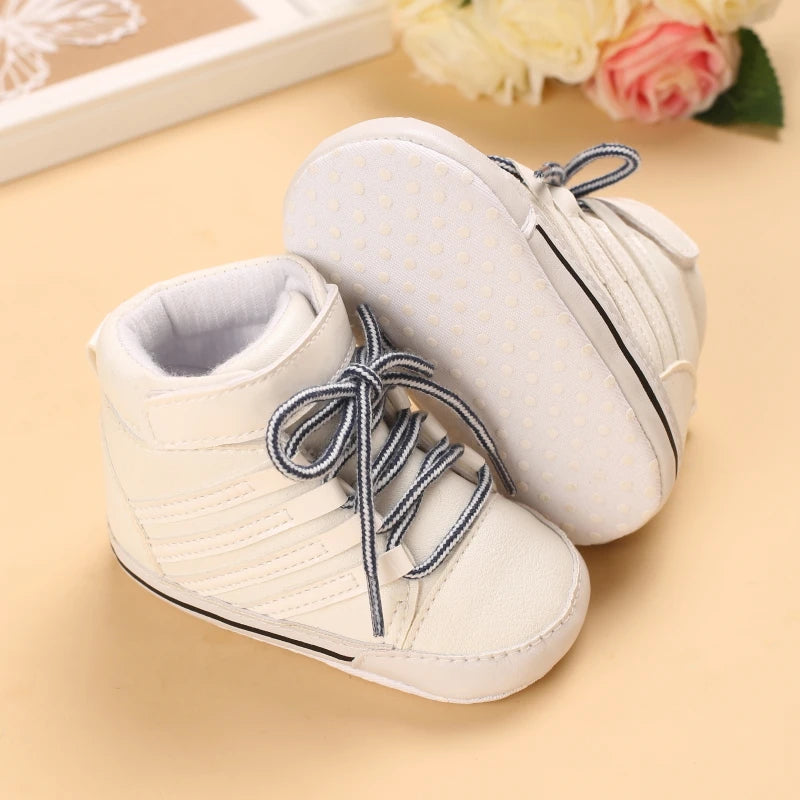 White baby shoes with blue laces on a beige surface