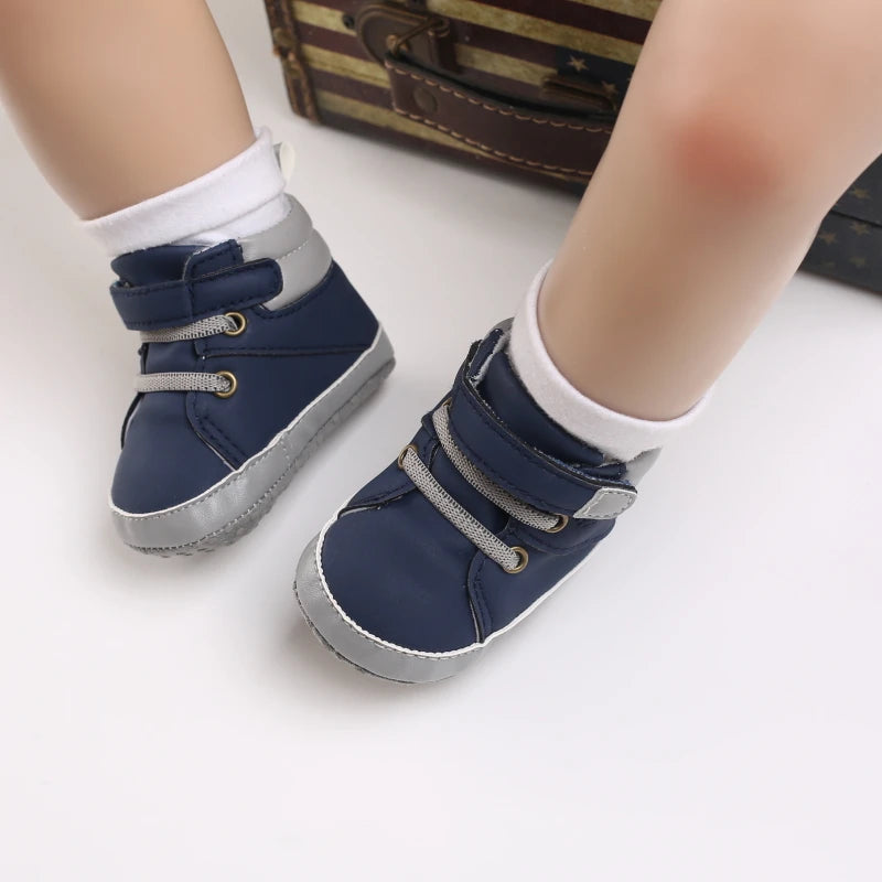 Navy blue baby shoes with gray soles worn by a child on a white background