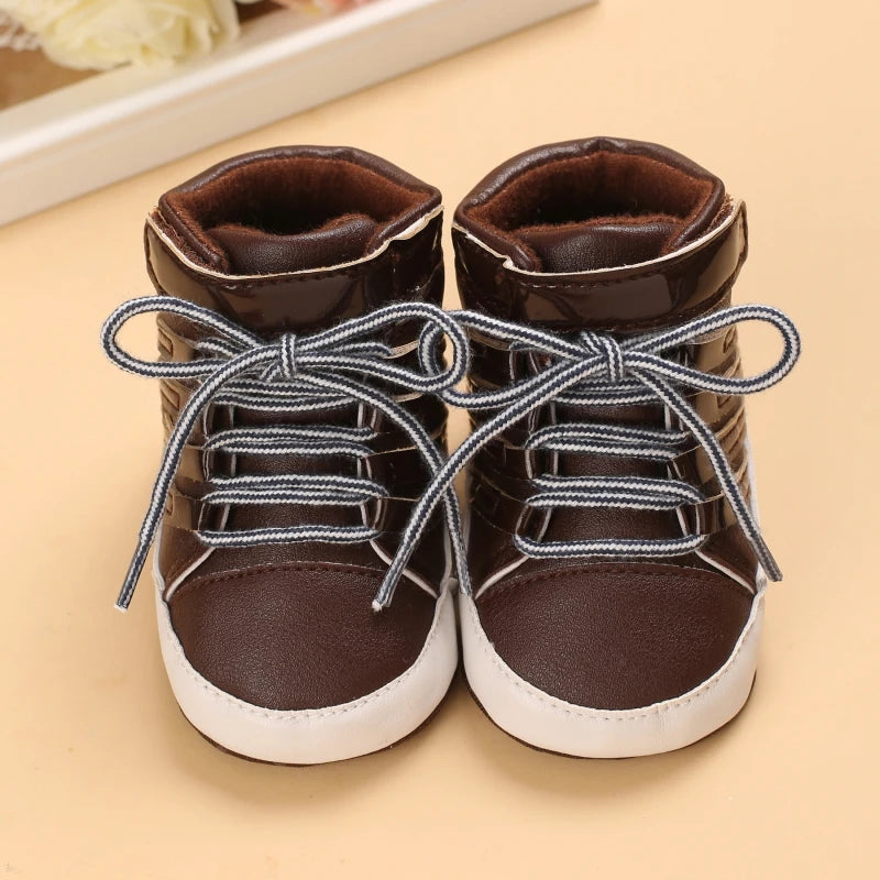 Pair of brown children's shoes with white soles on a beige background