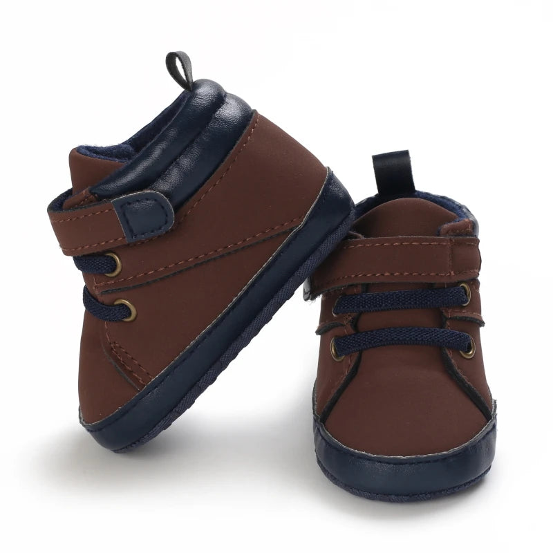 Pair of brown and navy baby shoes on a white background