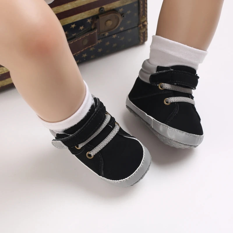 Black baby shoes with white socks on a light background