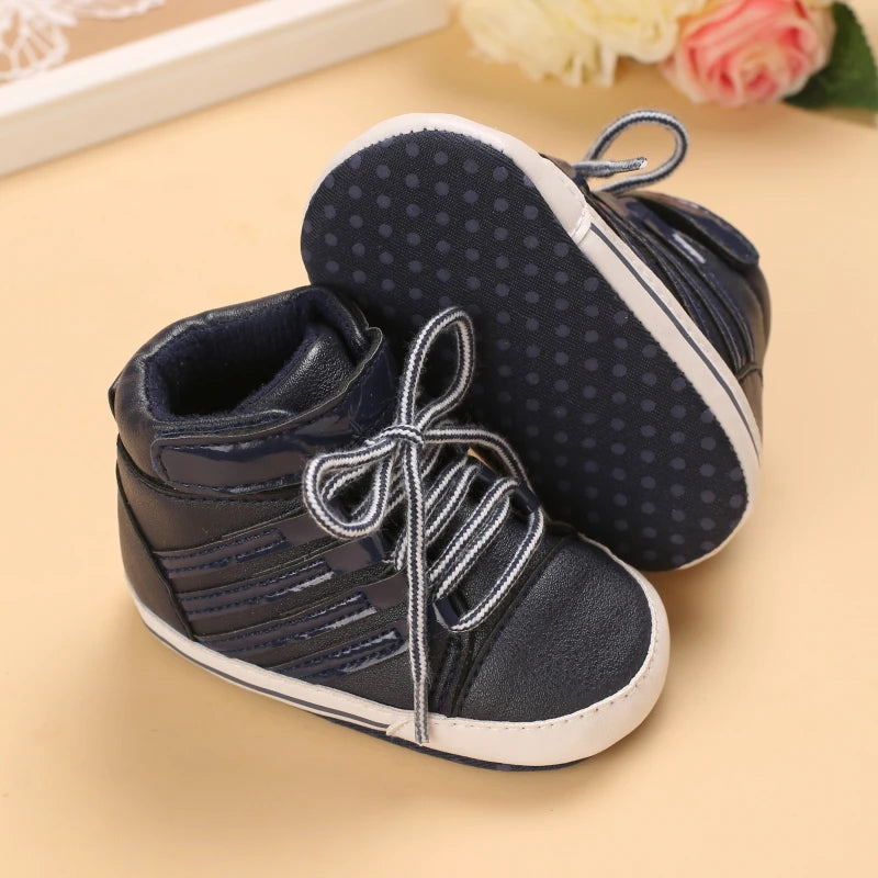 Pair of navy blue baby shoes with white soles on a beige background