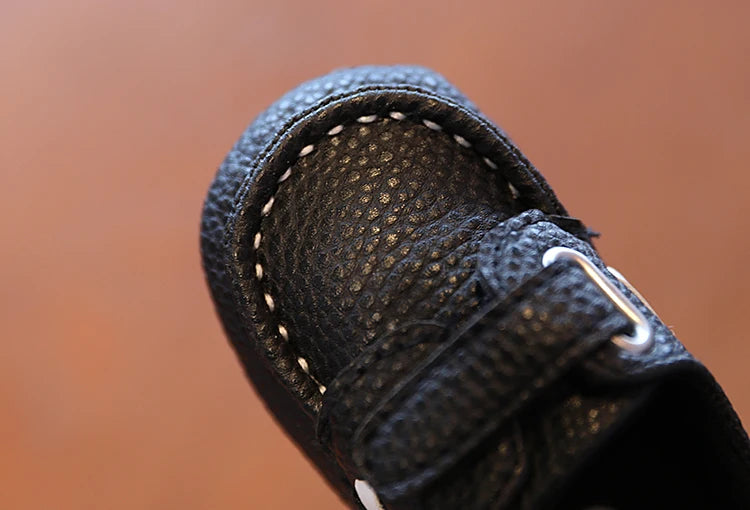 Close-up of a black shoe with a velcro strap on a blurred brown background