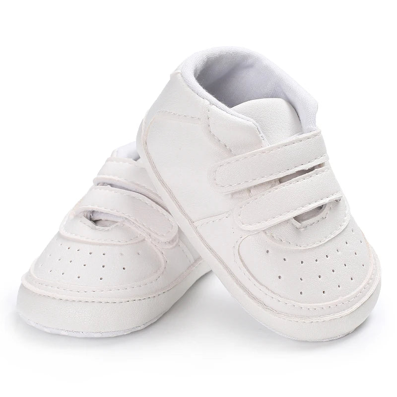 White baby sneakers with velcro straps on a white background