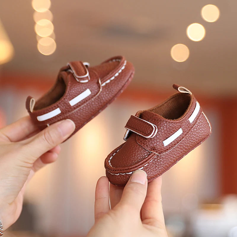 Brown children's shoes with velcro straps held by a person against a blurred background