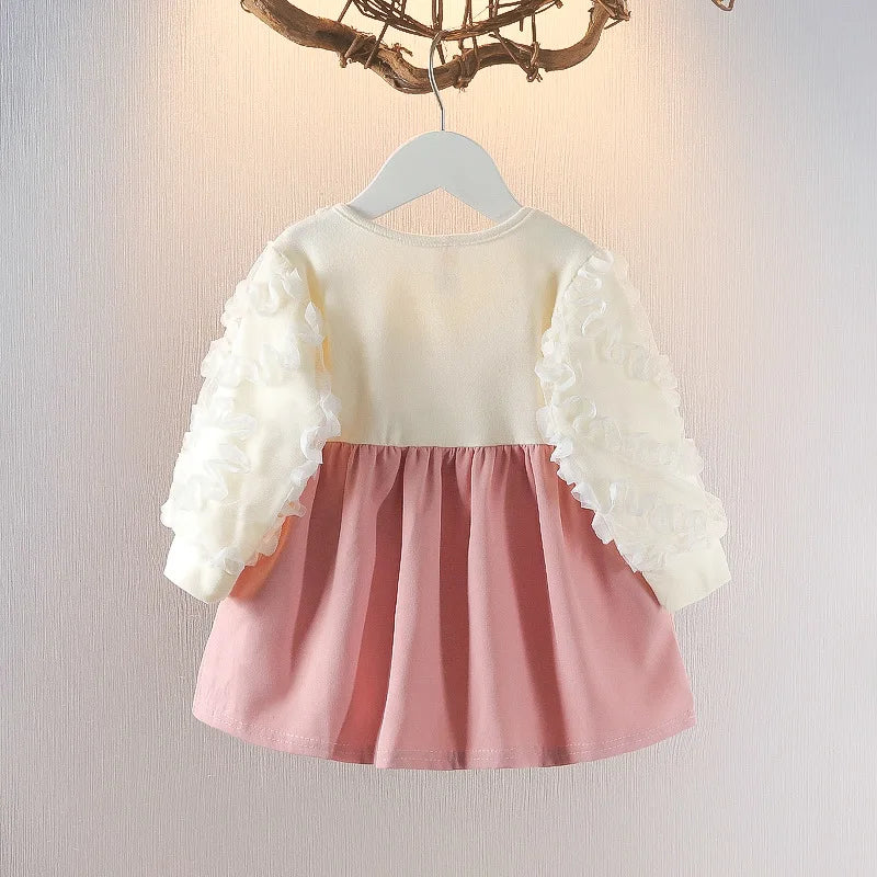 Children's dress with white lace sleeves and pink skirt on a hanger against a neutral background