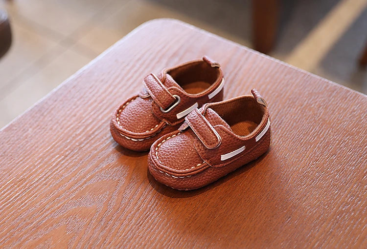 Pair of brown children's shoes on a wooden surface