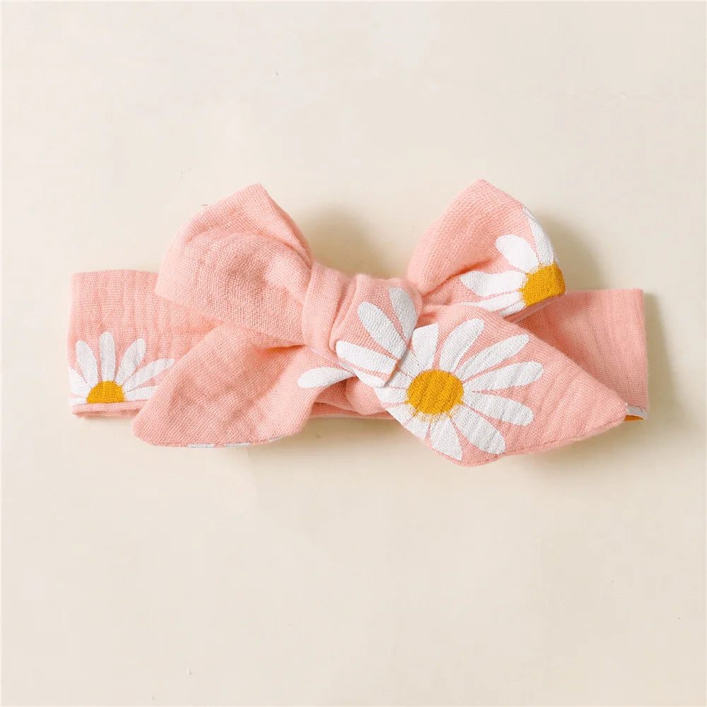 Pink headband with white daisy flowers on a beige background