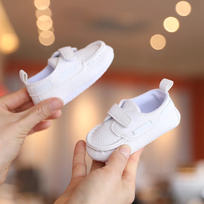 White baby shoes held by a person with a blurred background