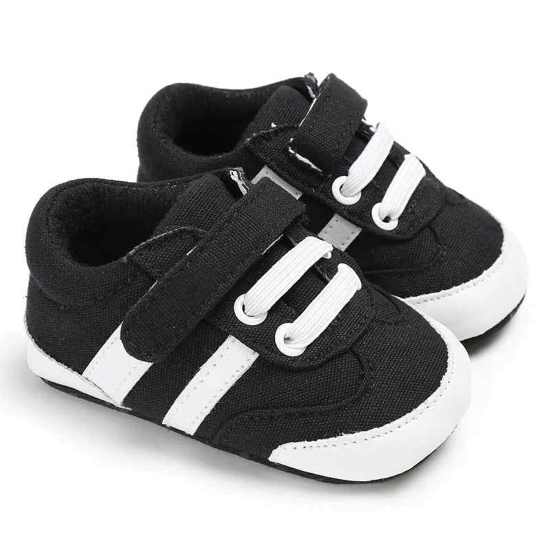 Black and white baby sneakers with velcro straps on a white background