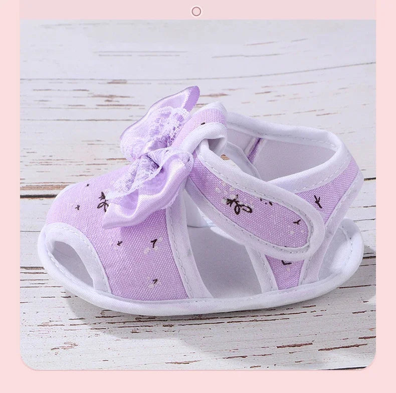 Purple baby shoes with a bow on a light wooden surface