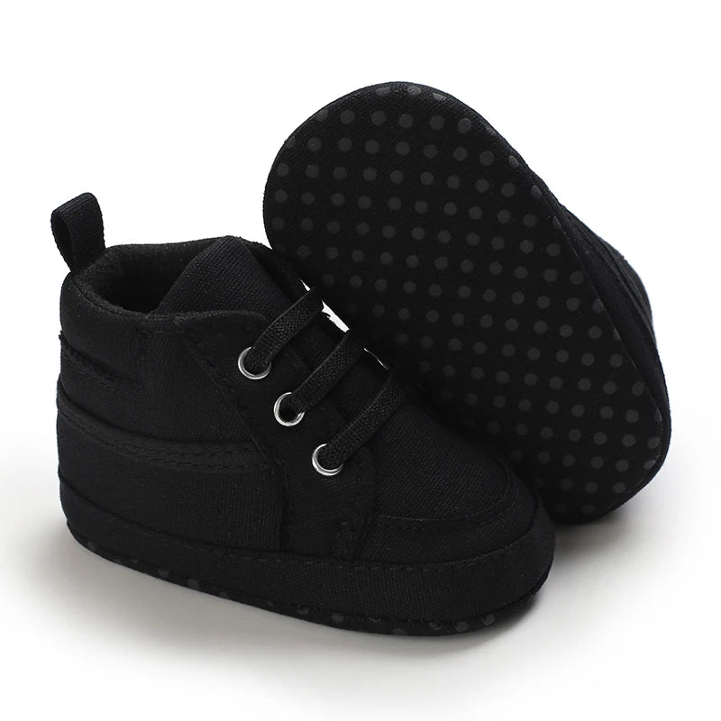 Black baby shoes with textured sole on a white background