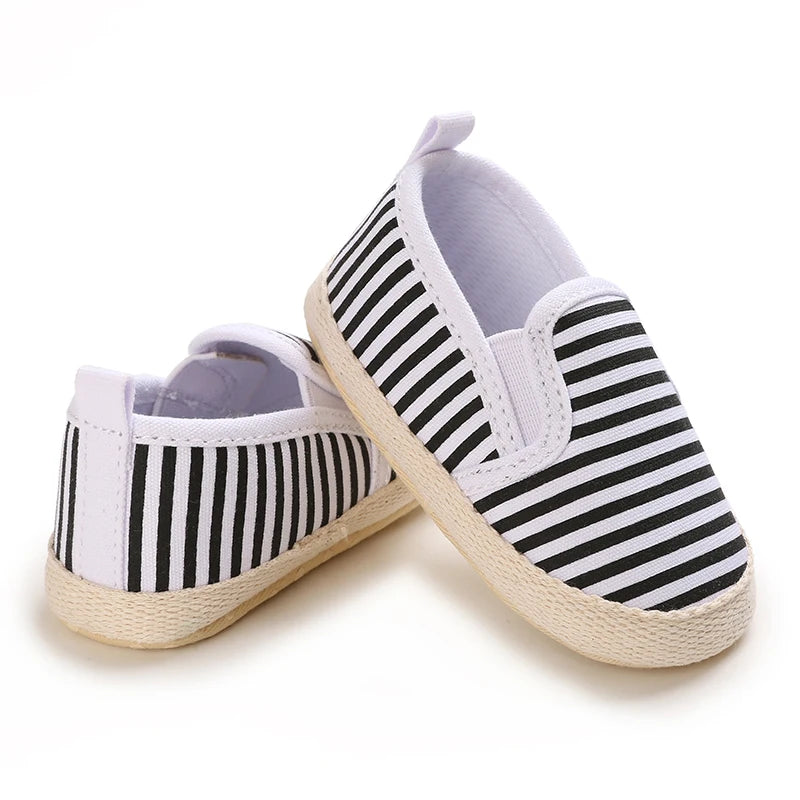 Pair of black and white striped baby shoes on a white background