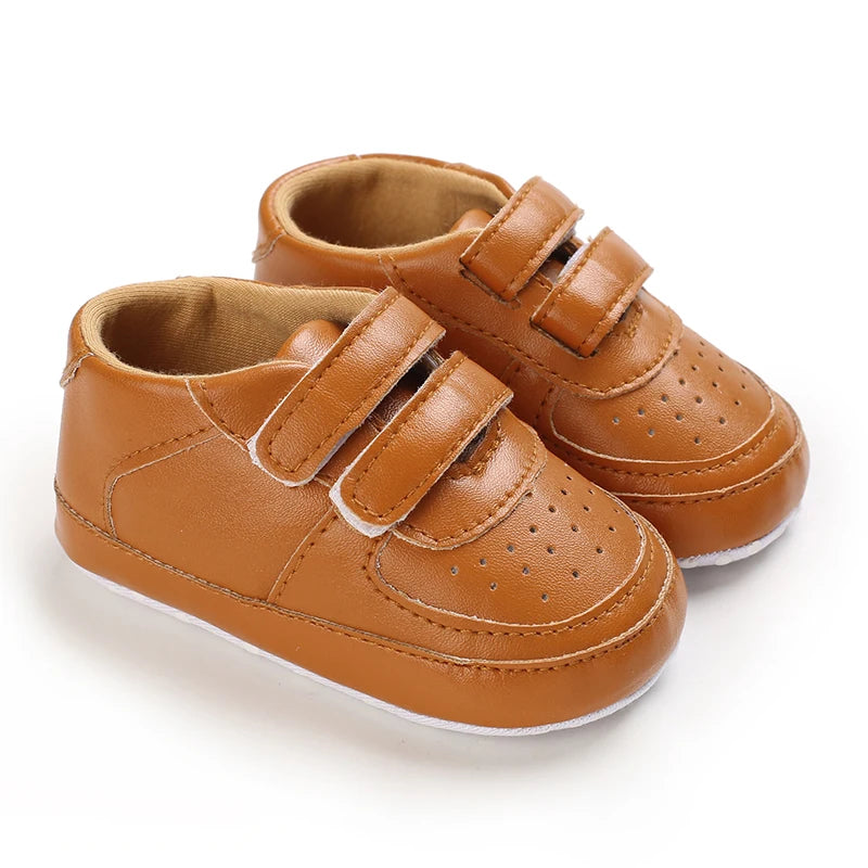 Pair of brown baby shoes with velcro straps on a white background
