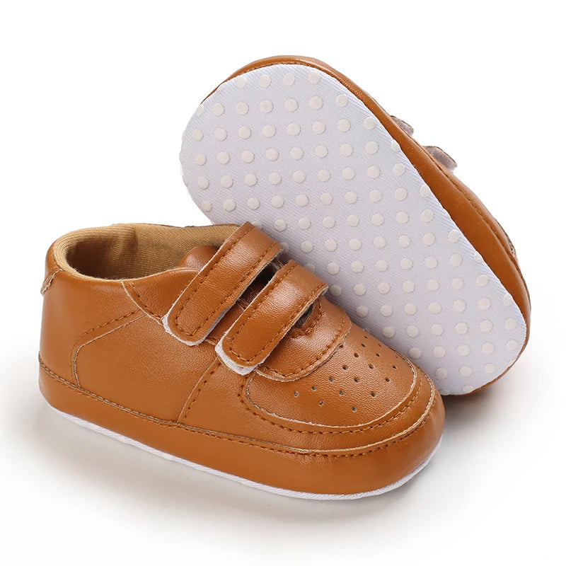Brown baby shoes with white sole on a white background