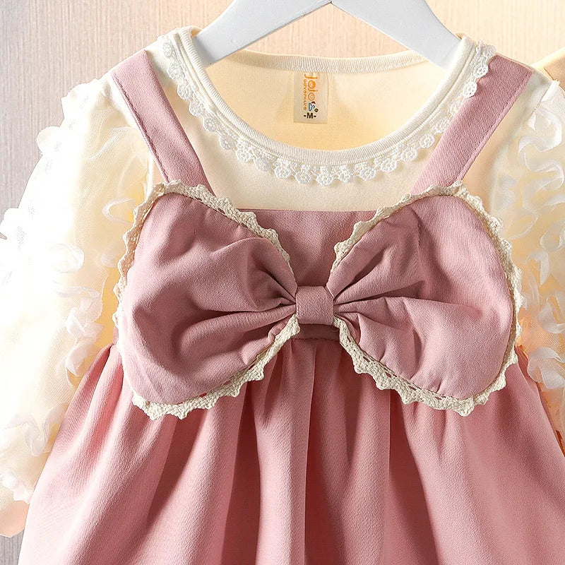 Pink dress with a large bow on a hanger against a neutral background
