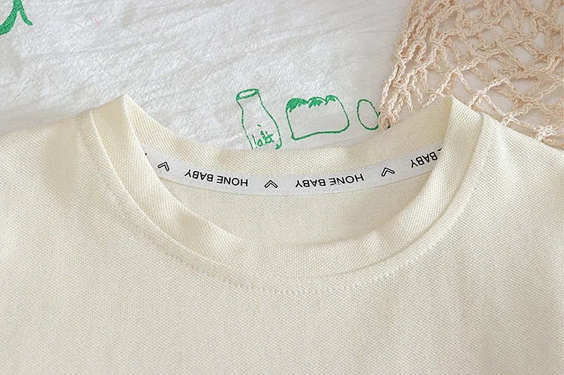 Close-up of a white garment with green illustrations and text on the collar.