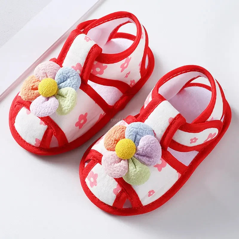 Pair of red baby sandals with colorful flower designs on a white background