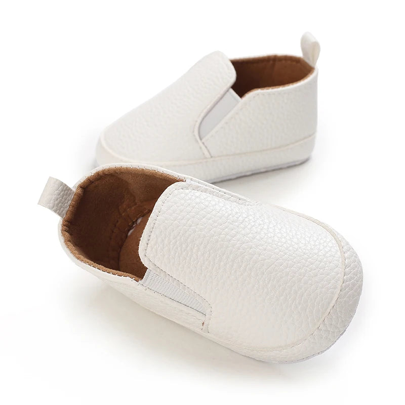 White baby shoes with brown soles on a white background