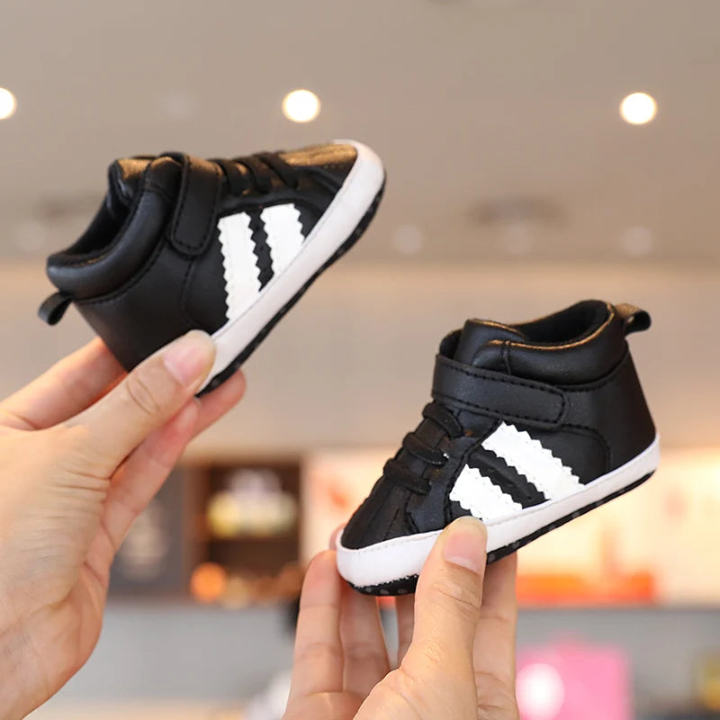 Black and white sneakers held by a hand with a blurred indoor background