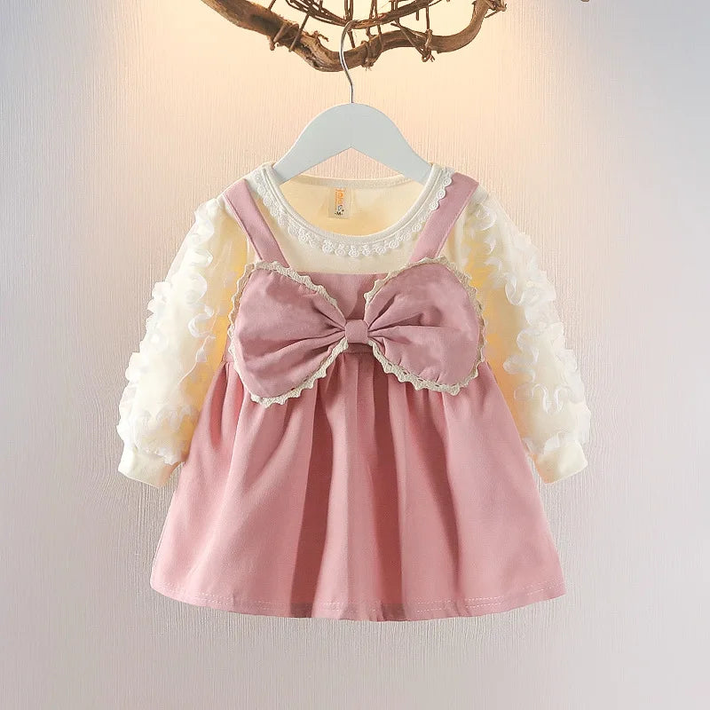Pink dress with a large bow on a hanger against a light background