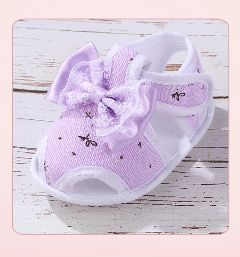 Purple baby shoes with a bow on a wooden surface