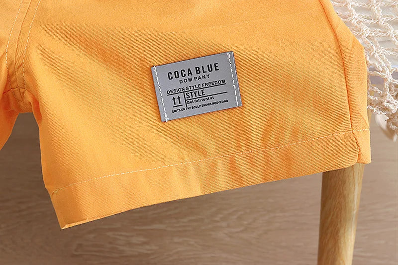 Close-up of a yellow shirt with a Coca Blue label on a blurred natural background