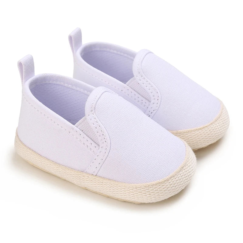 Pair of white baby shoes with light brown soles on a white background