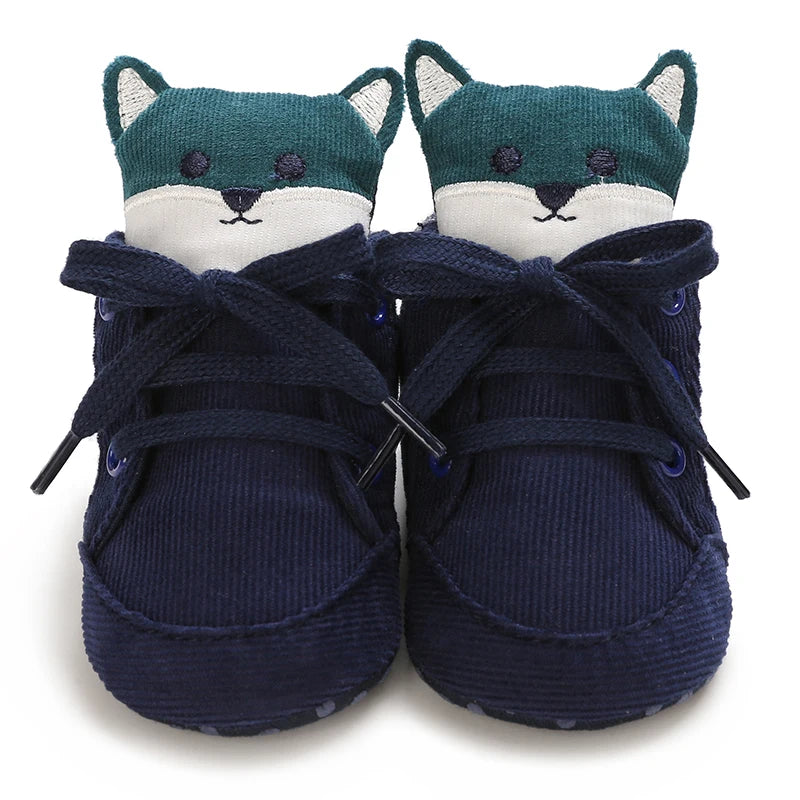 Pair of navy blue baby shoes with cat face design on a white background