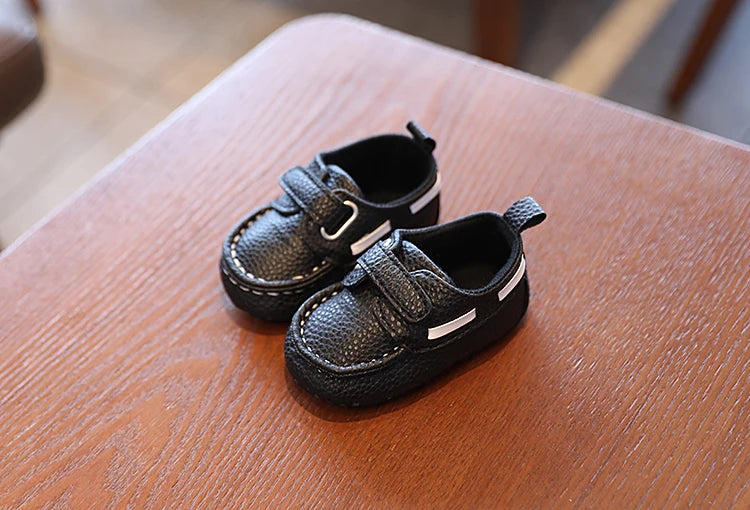 Pair of black children's shoes on a wooden surface
