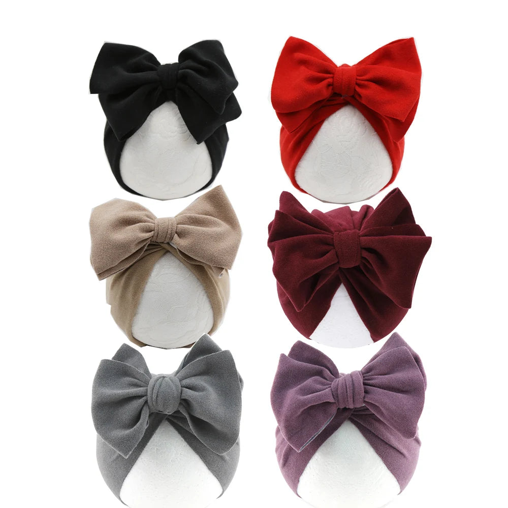 Set of six baby headbands with large bows in various colors on a white background
