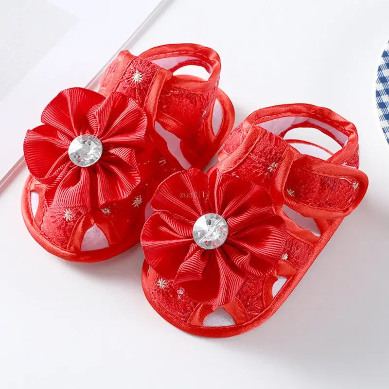 Red children's sandals with floral designs and rhinestones on a white background