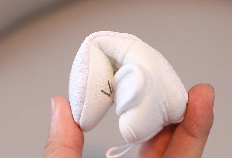 White plush toy held in a hand against a neutral background