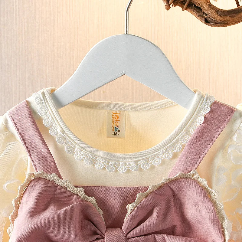 Pink dress with lace details on a hanger against a beige background