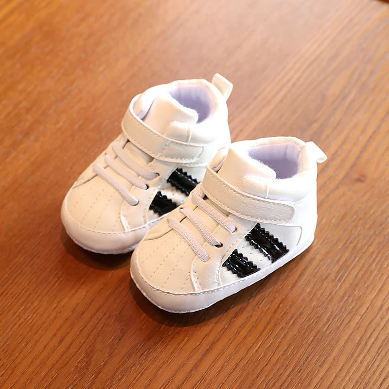Pair of beige high-top sneakers with black stripes on a wooden surface