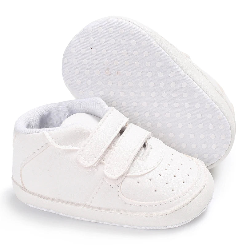 White baby sneakers with velcro straps on a white background
