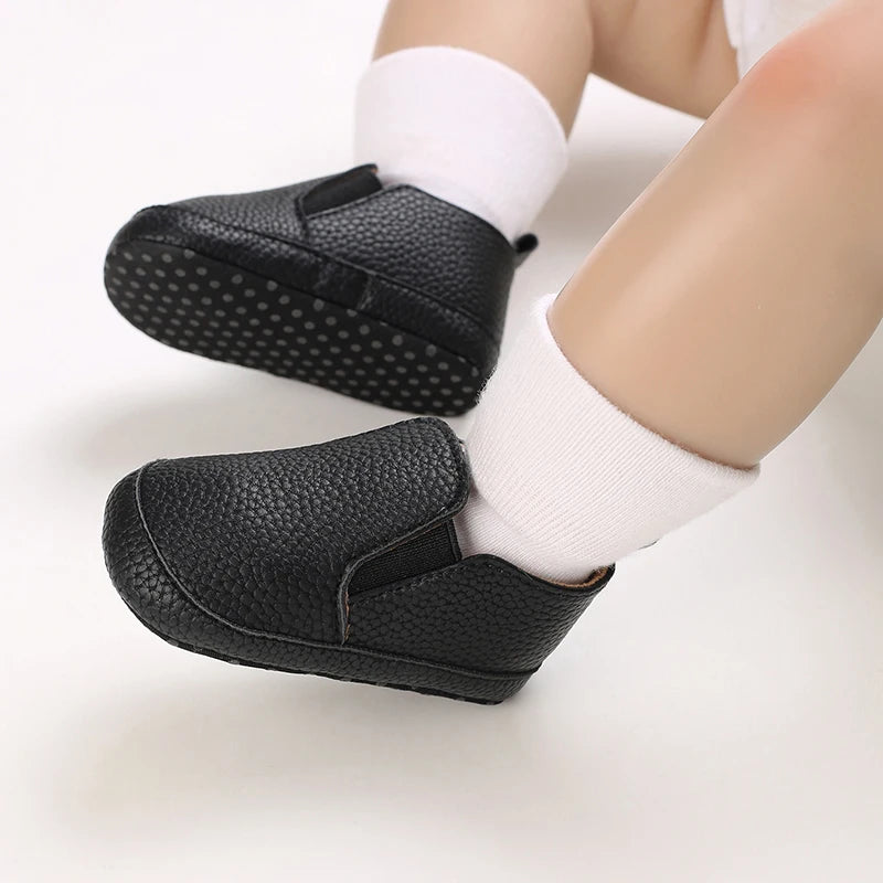 Black baby shoes with white socks on a light background