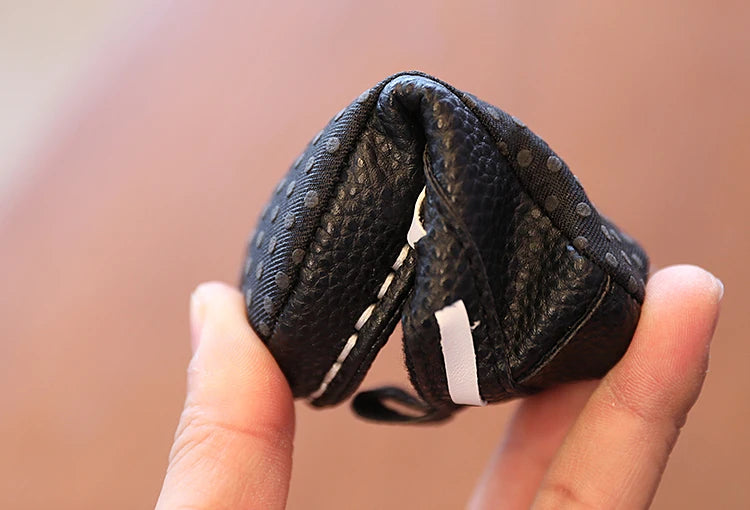 Hand holding a small black textured pouch against a blurred background