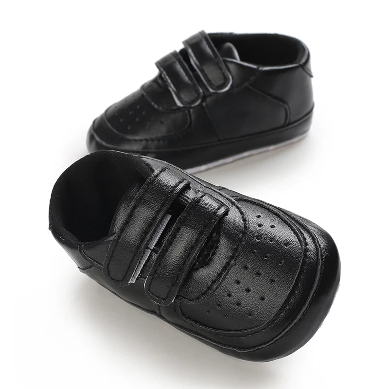 Pair of black baby shoes with velcro straps on a white background