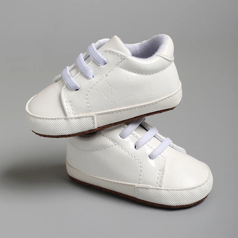White children's shoes with light purple laces on a gray background
