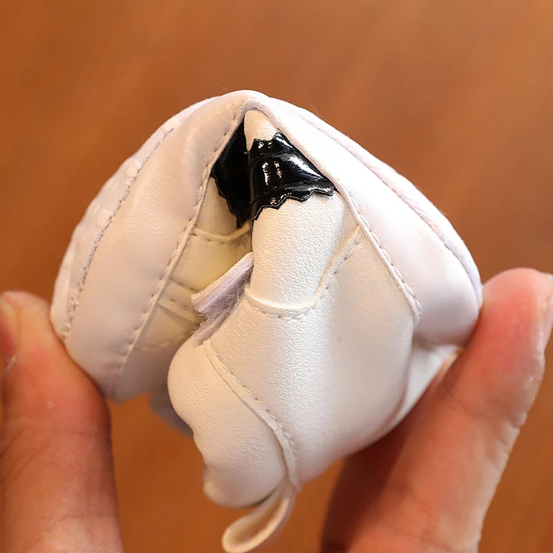 White boxing glove with a black patch held between fingers against a brown background