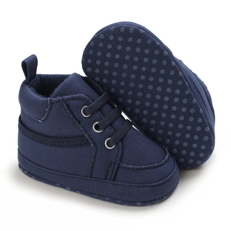 Navy blue baby shoes with polka dot soles on a white background