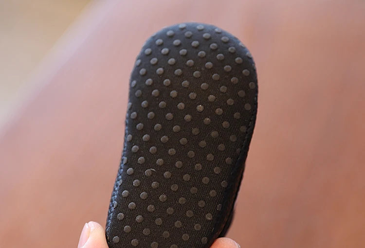 Close-up of a black shoe sole with textured pattern held by a hand against a blurred background