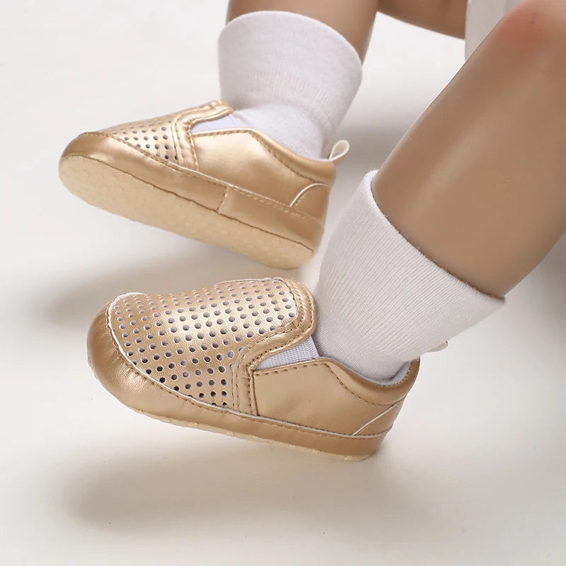 Gold baby shoes with white socks on a light background